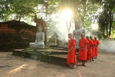 Singburi Province, Thailand - 26 November 2023: Novices are walking and meditating around the Buddha statue in the morning clipart