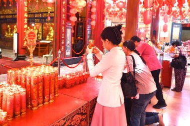 Çin Mahallesi, Yaowarat Yolu, Bangkok, Tayland - 21 Ocak 2025: Çinli bir kadın Çin Yeni Yılı sırasında Çin Tapınağı 'nda mum yakarken dua ediyor