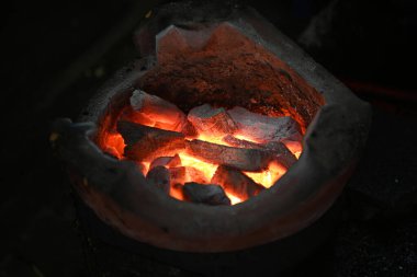 Karanlık bir arka planda yerel bir ocakta yanan kömürün yakın plan çekimi.