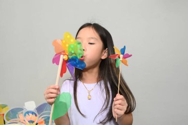 Renkli bir yel değirmeni tutan şirin bir Asyalı kızın portresi. 