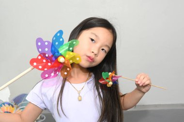 Renkli bir yel değirmeni tutan şirin bir Asyalı kızın portresi. 