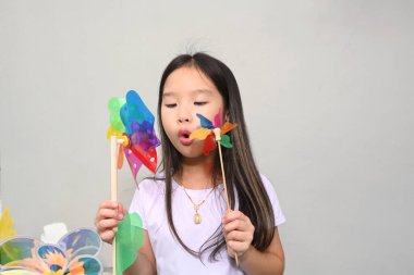 Renkli bir yel değirmeni tutan şirin bir Asyalı kızın portresi. 