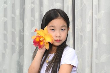 Renkli bir Cattleya orkidesi olan şirin bir Asyalı kızın portresi.
