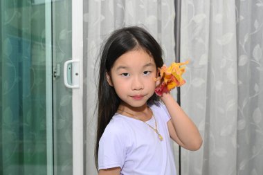 Renkli bir Cattleya orkidesi olan şirin bir Asyalı kızın portresi.