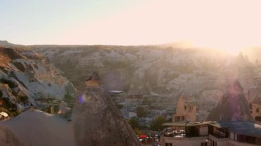 Güneş, Goreme, Nevsehir, Türkiye 'nin üzerinde batıyor. Gün batımında Kapadokya. Kasaba manzarası, peri bacaları ve Uchisar Kalesi ufuk çizgisinde. UNESCO Dünya Mirası