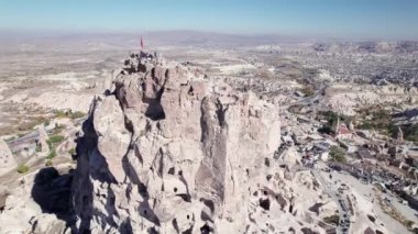 Uchisar Kalesi 'nin hava dairesel manzarası. Kapadokya' nın kaya ve manzarası. Uchisar mağara kasabasının tepesinde bayrak sallanıyor, Kapadokya, Nevsehir, Türkiye. UNESCO Dünya Mirası