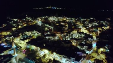 Aydınlatılmış sokakların havadan görünüşü ve Goreme köyündeki peri bacaları ve arka plandaki Uchisar kalesi kayaları.