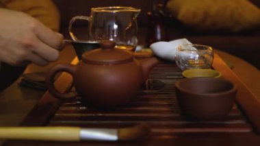 Brewing puerh tea. Person pours tea from yixing clay teapot to bowl at tea tray. Chinese traditional gongfu cha tea ceremony.
