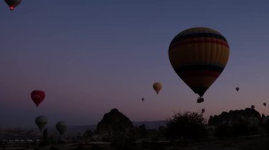 Kapadokya 'da güneş doğarken bacaların üzerinde uçan sıcak hava balonları.