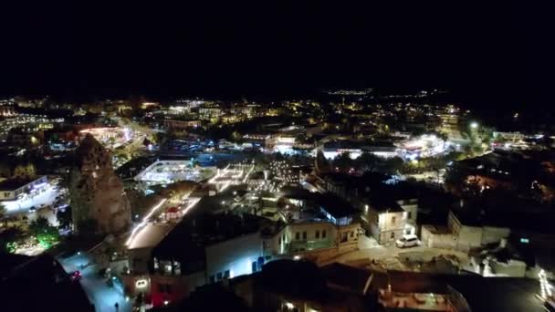 无人机在卡帕多西亚的开明洞穴酒店和摇滚酒店上空飞行 Goreme的夜灯 夜间童话烟囱和建筑物的空中景观 — 图库视频影像