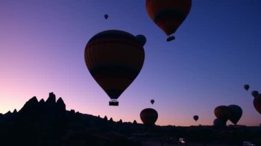 Kapadokya 'da güneş doğarken bacaların üzerinde uçan sıcak hava balonları.