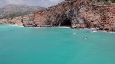 Aerial view of family supboarding down azure sea