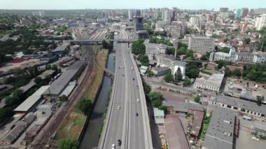 Cars drive on motorway built along river and railway. Aerial view of motorway and railway interchange