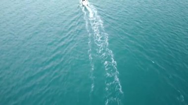 Aerial view of motorboats sail on sea leaving wake trails. Boats go to beach