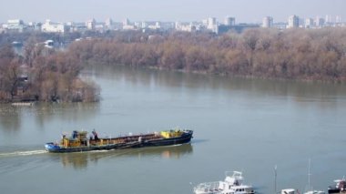 Cargo ship sailing on the river. Bulk carrier sails down the Sava river, Belgrade, Serbia. Handheld real time footage of barge sailing down the river
