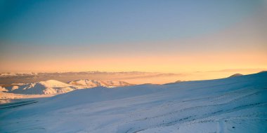 Akşam güneşinin ışınlarıyla kaplı dağ yamaçları. Bir dağ yamacında gün batımı. Kış manzarası. Erciyes mount, Kayseri, Türkiye