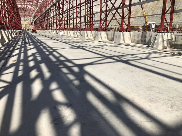 Truss ceiling and metal pillars and girders cast shadow on concrete floor. Support constructions. Industrial building metal framework. Low angle view