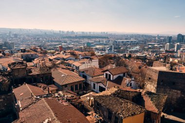Ön plandaki tarihi binaların kiremitli çatılarının panoramik manzarası ve arka plandaki modern yüksek binalar. Ankara 'nın panoramik manzarası Ankara kalesinden görüldü