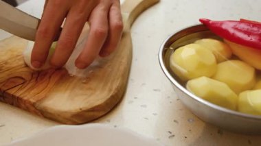 Erkek elleri soğan doğruyor. Kesme tahtasında soğan doğramak. Evde yemek pişirmek.