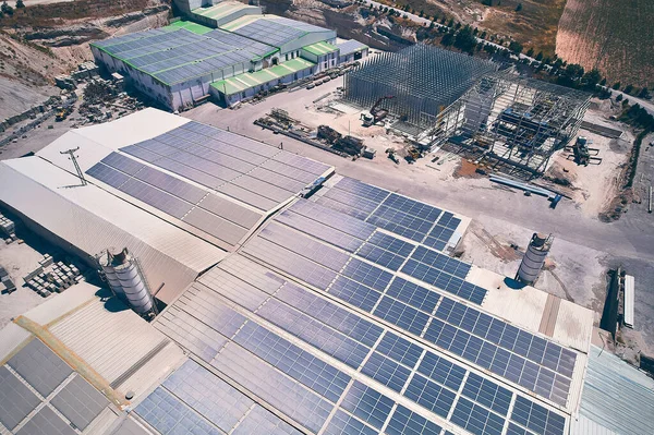 Aerial view of industrial buildings with photovoltaic panels installed on roof. Solar panels on industrial building roof. Solar PV panels aerial view