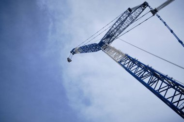 Büyük vinç alttan yukarı doğru görünüyor. Gökyüzü bulutlu, alçak açılı, turna patlaması. Ağır kaldırma makineleri 