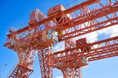 Gantry vinçleri bulutlu gökyüzünün karşısında. Endüstriyel kaldırma makineleri