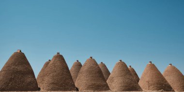 Traditional mud brick or adobe made beehive houses. Harran, major ancient city in Upper Mesopotamia, nowadays is a district in Sanliurfa province, Turkiye. Roofs of beehive houses opposite clear sky