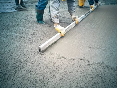 Construction worker uses trowel to level cement mortar screed. Concrete works on construction site. Cast-in-place work using trowels.  clipart