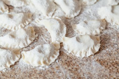 Granit tezgahın üzerinde beyaz un içinde çiğ hamur köfteleri var.