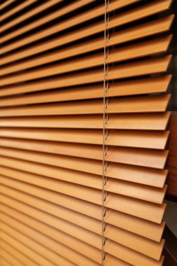 Horizontal wooden blinds of yellow color from narrow slats in the closed position close-up. Shot at an angl