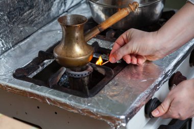 Pirinç Turk bir gaz sobasının üstünde duruyor. Sağ el, gaz sobasını yanan kibritle yakar.