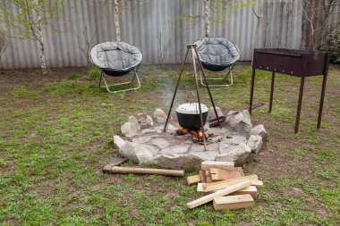 Ekipmanlı piknik alanı. Çayırda yuvarlak taştan bir kamp ateşi yakıldı. Esrar tezgahın üzerinde duruyor. Yakınlarda bir Brezilyalı ve iki yuvarlak koltuk var.