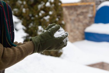 Kış eğlencesi Yeşil yün eldivenli eller, soğuk bir günde kar topları oluşturur.