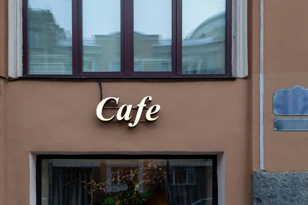 stock image Laconic luminous inscription cafe on wall of city building between windows. Street sign is located on brown finish of the facad