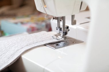 Hafif kumaş modern bir dikiş makinesinde bulunur. İğne demiri dikişleri tamamlıyor. Kapat.