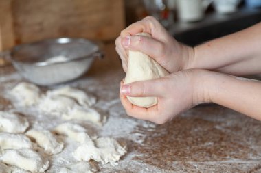 Bir kadın eli granit tezgahta bir parçayı eziyor. Arka planda beyaz yüzgeçli hamur tatlısı var.