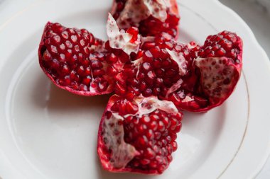 Kırık nar ve olgun kırmızı taneler beyaz bir fiyonkta yatıyor.