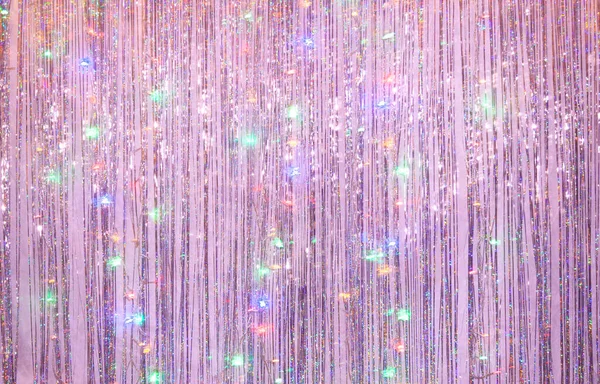 Photo zone for a Christmas party. Background for photography from lilac tinsel and blurry lights of a luminous garland at a long exposur
