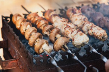 Izgara yapıyorum. Metal bir ızgarada bir sıra mantarlı şiş yatıyor.