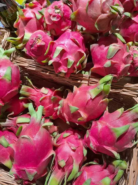 Many dragon fruits lie in wicker baskets on sale in a supermarket. Pitahaya or pitaya is the common name for the fruits of several species of cacti from the genera Hylocereus and Stenocereus