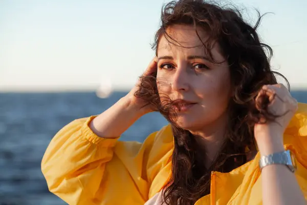 stock image Nice girl with long red hair is standing on the background of a water surface. Portrait of a woman without retouching with her natural imperfection