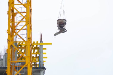 İnşaatta vinçe asılı beton döken baca.