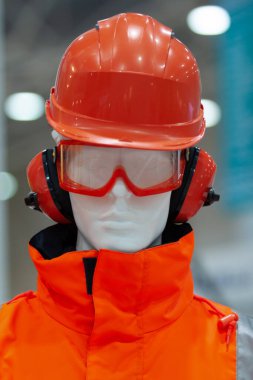 Turuncu kolorosuyla çalışan bir inşaat işçisinin koruyucu ekipmanındaki bir mankenin yakın plan portresi.