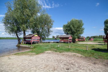 Nehirde dinlenmek için uygun bir yer. Kıyı boyunca tahta ağaçlar ve uzun ağaçlar var.