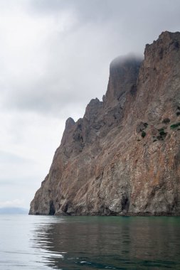 Resimli bir manzara. Deniz, dağlar, kalın bulutlar. Sudan görüntüle