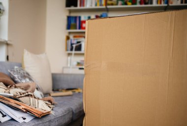 Oturma odasında kanepenin yanında büyük bir karton paket var.