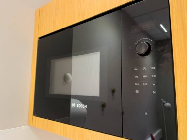 Paris, Fransa - 20 Ekim 2022: Siyah cam ve beyaz düğmeli modern Bosch mikrodalga fırının yan görüntüsü - küçük mutfağın yansıması