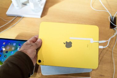 Paris, Fransa - 28 Ekim 2022: Yeni Apple Bilgisayarları iPad kullanan adam mağazada sarı renkli 10. nesil - arka kameraya bakıyor