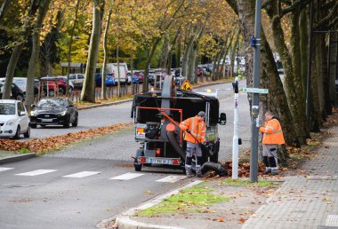 Strasbourg, Fransa - 22 Kasım 2022: Sonbahar boyunca kaldırımları süpüren işçiler, enkaz ve yaprakları emmek için güçlü elektrik süpürgesi kullanıyorlar