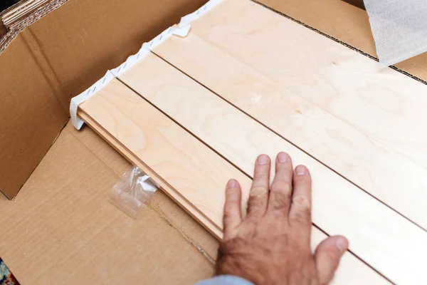 Male hand unboxing wooden slats of a bed base of a luxury new bed